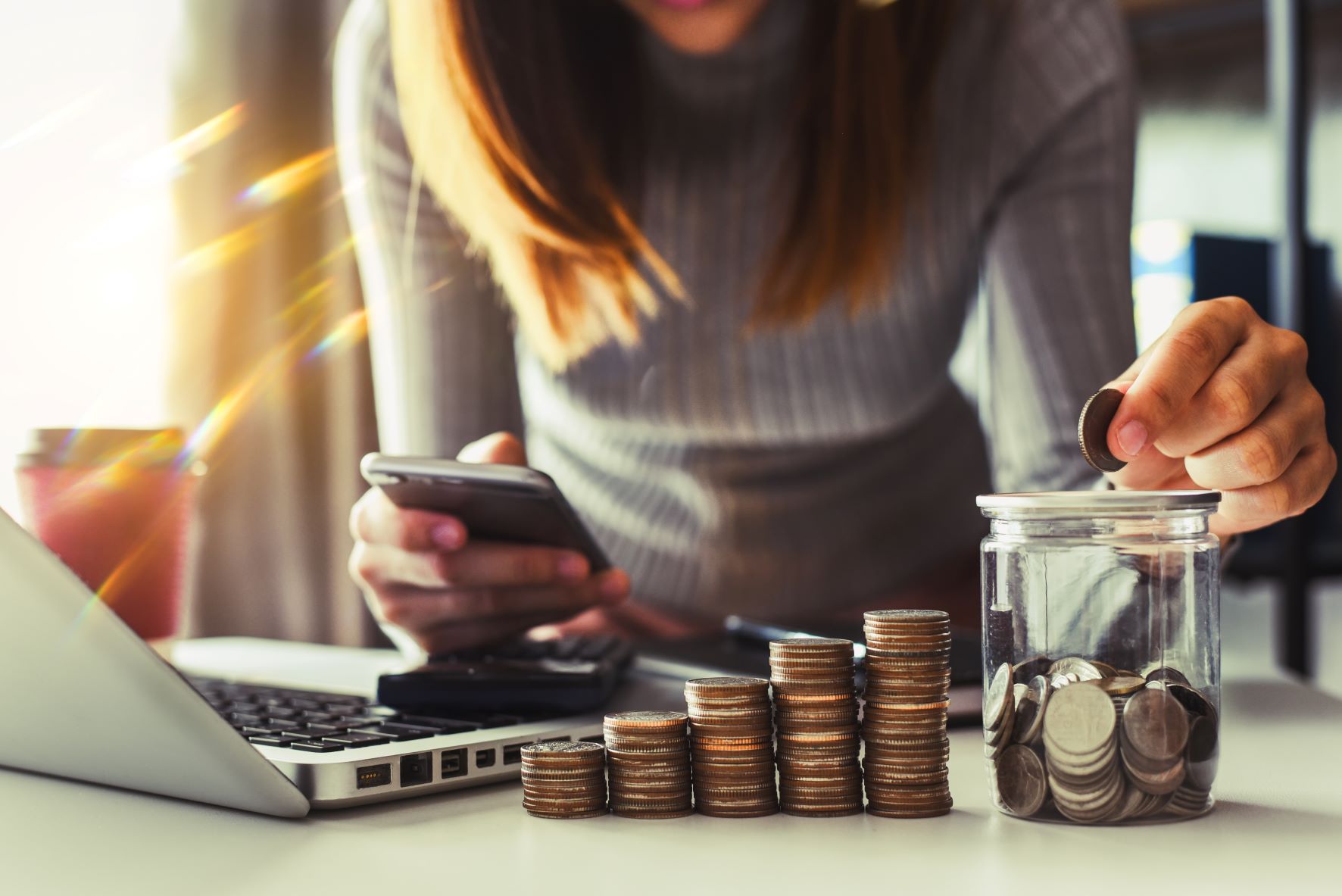 woman stacking coins next to a jar for savings